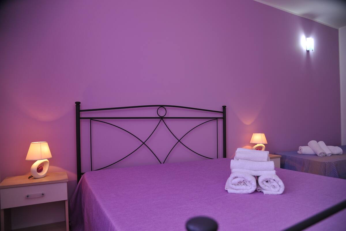 A room with a bed, two nightstands, and a wall-mounted light fixture.