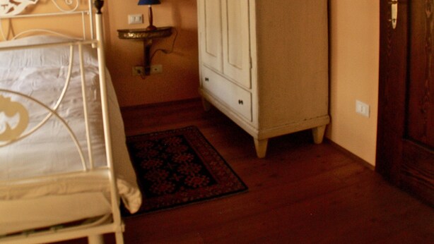 A bedroom with a bed, a bedside table with a lamp, a wardrobe, and a door.