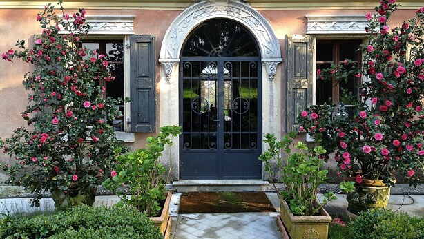 A historic building with a black iron gate, ornate stone archway, and potted rose bushes. - Ca' Marsure B&B (Azzano Decimo)
