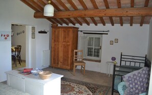 Une pièce chaleureuse avec un plafond en bois, un lit, une petite table avec un bol, une chaise et une fenêtre avec des rideaux.