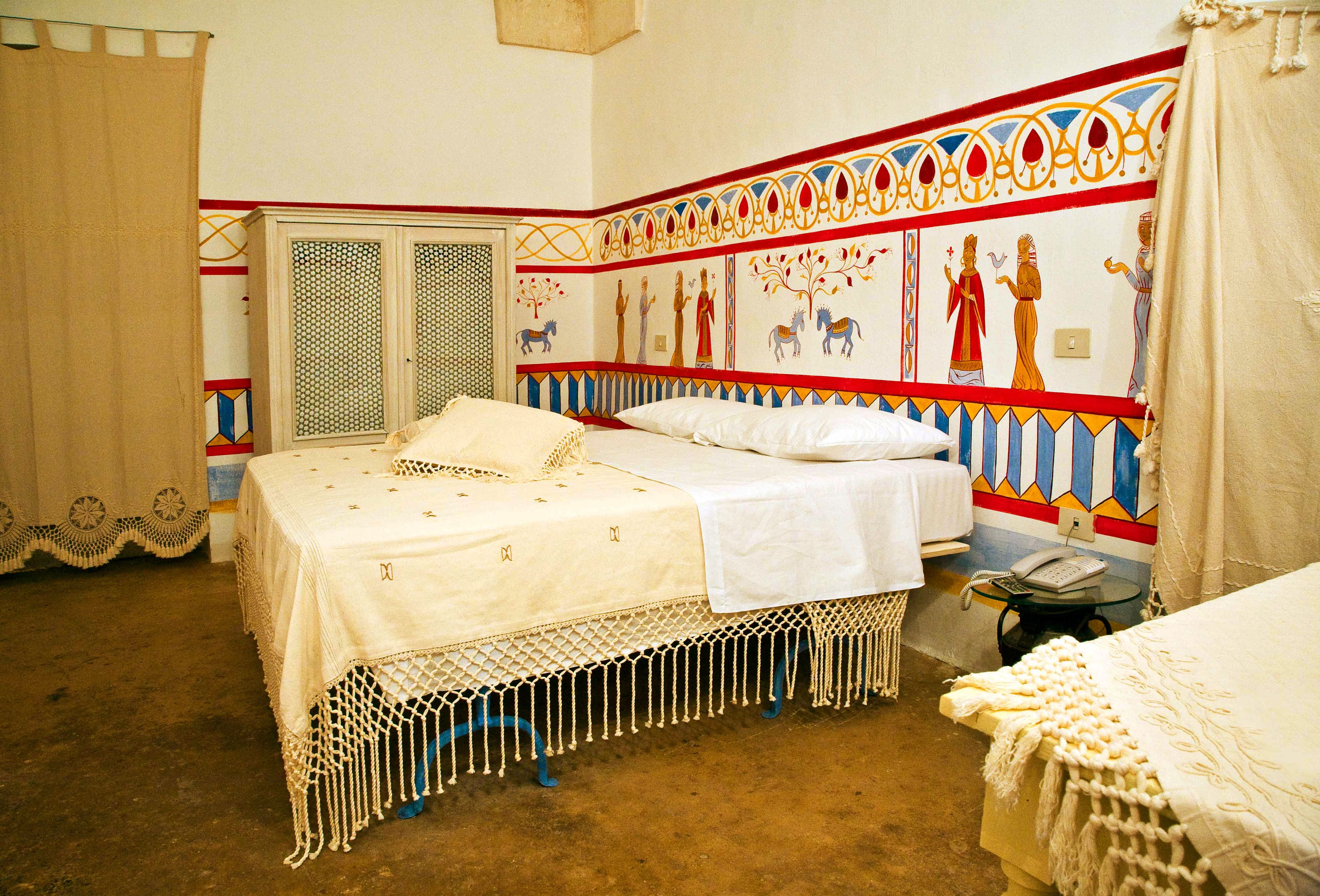 A room with a bed, a small table, and a wall with decorative patterns.