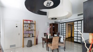 Un comedor moderno con una mesa de madera, sillas de mimbre y una estantería con diversos objetos.