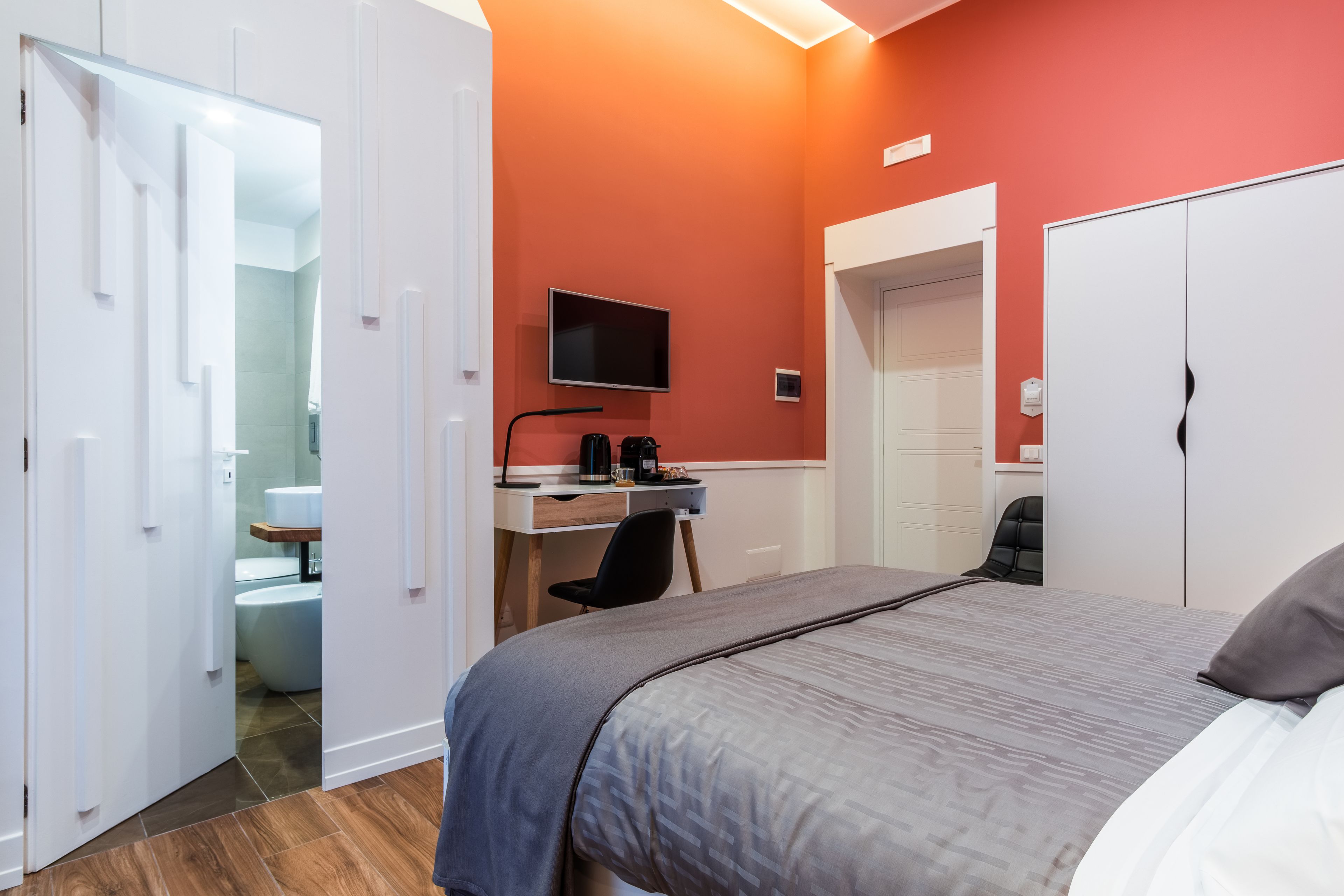 Una camera da letto con un letto, una scrivania con un computer, una televisione e un armadio.