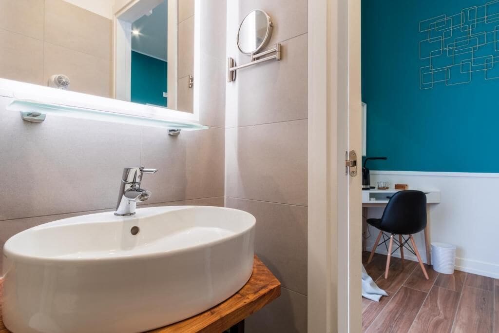 A modern bathroom with a large white sink, a mirror, and a wooden vanity.