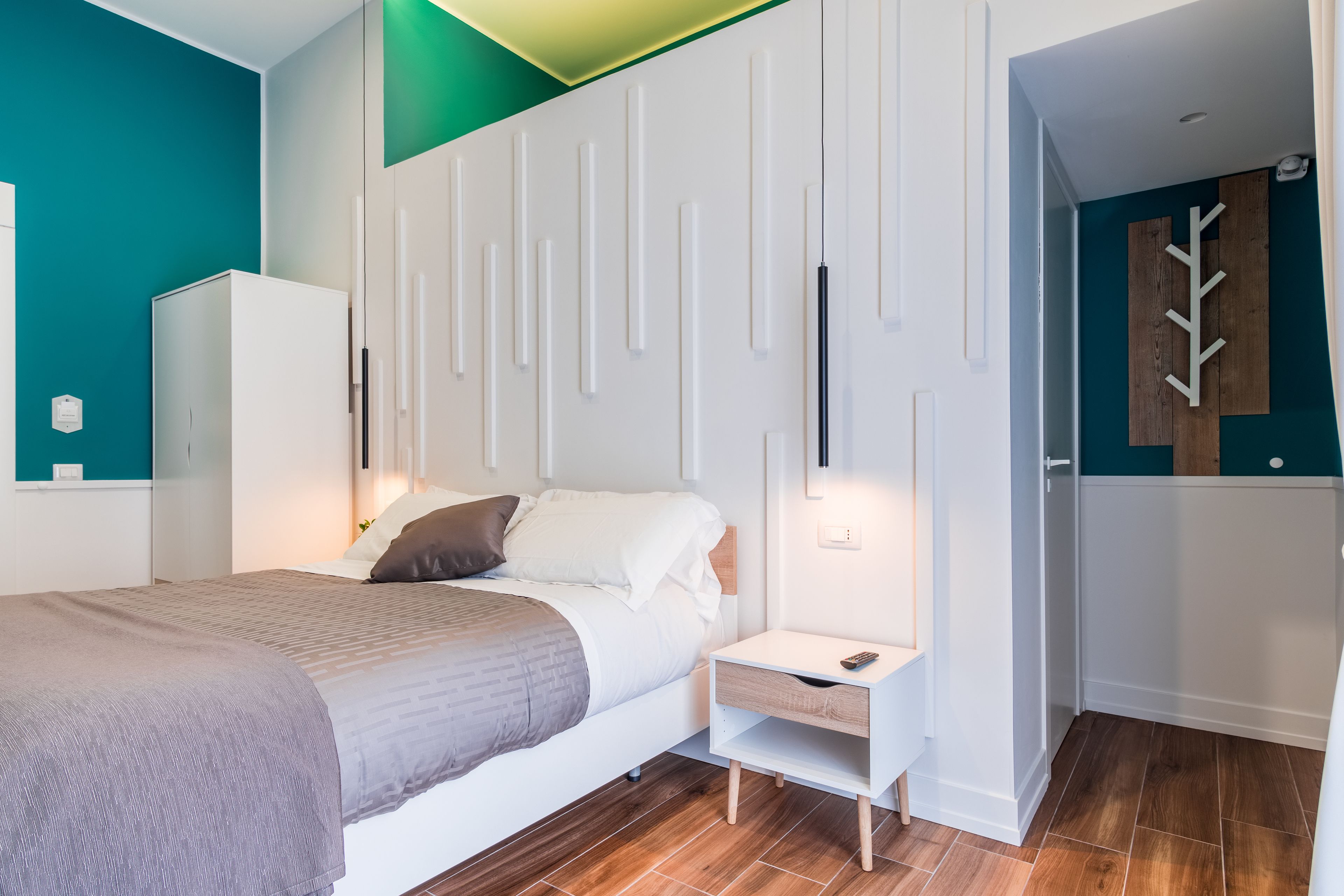 A modern bedroom with a bed, nightstand, and wardrobe.