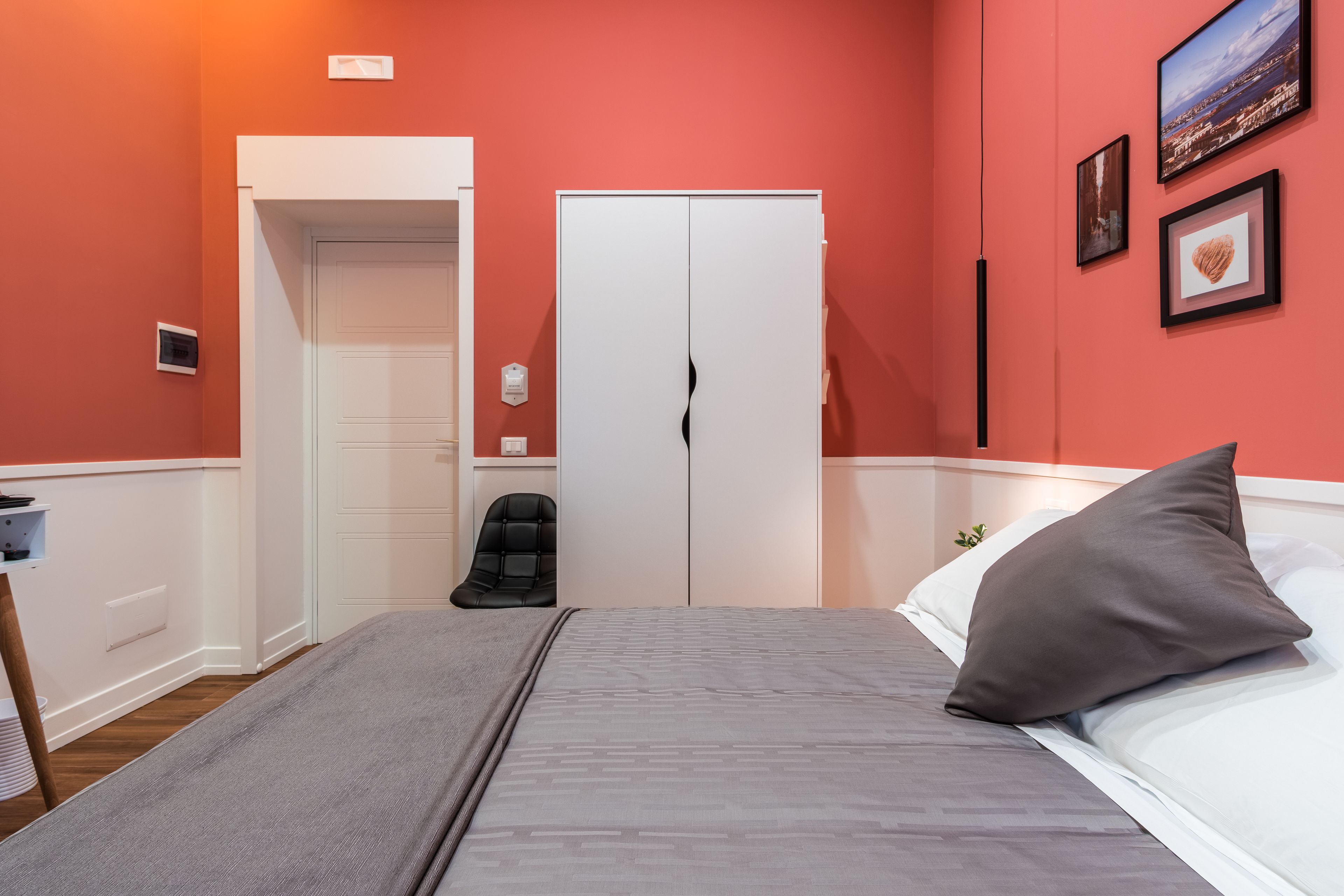A bedroom with a bed, a chair, a wardrobe, and a door.