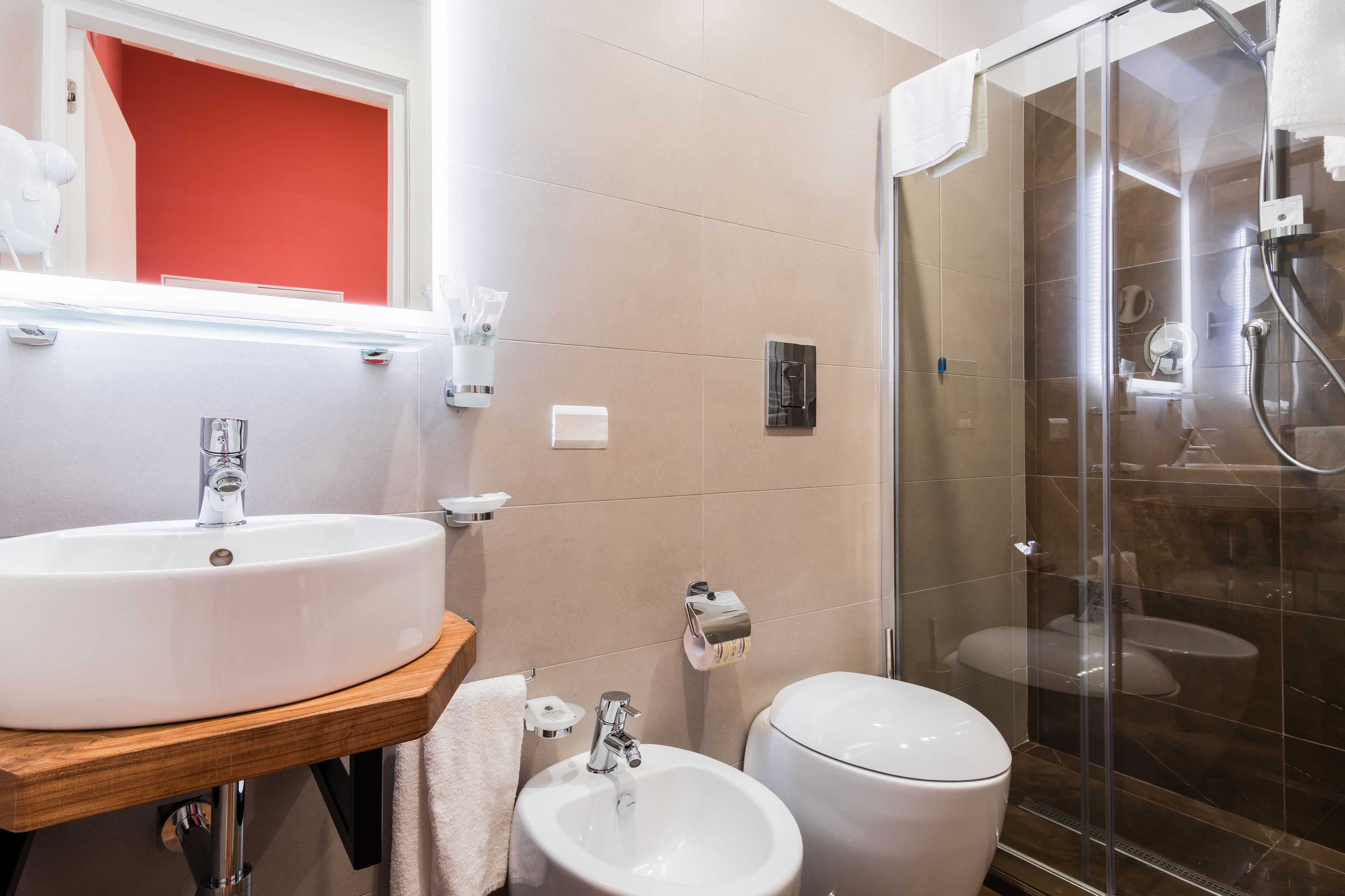 Une salle de bain moderne avec un lavabo blanc, un bidet et une douche à parois de verre.