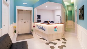 A reception area with a reception desk labeled "VistaViva," a potted plant, and a staircase leading to another floor. - VistaViva B&B (Naples)