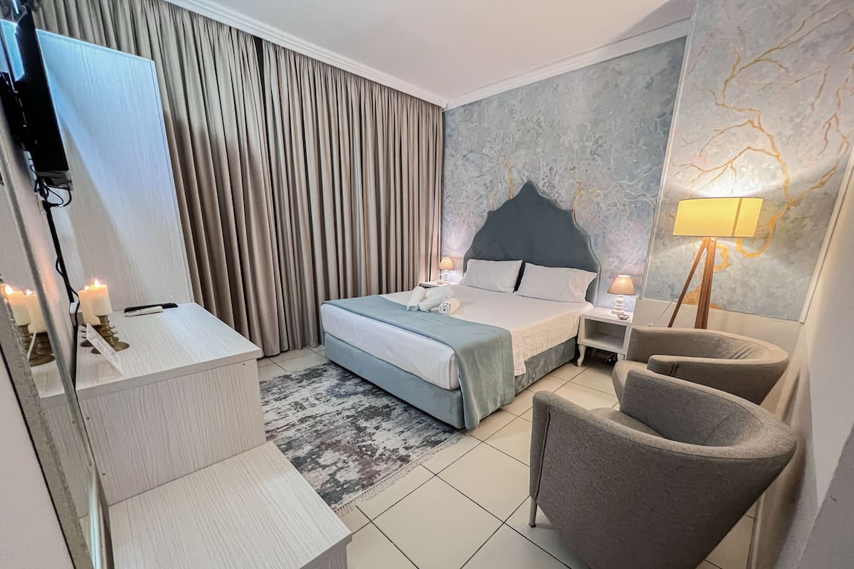 Una habitación de hotel moderna con cama, mesitas de noche, escritorio, silla y un espejo grande.