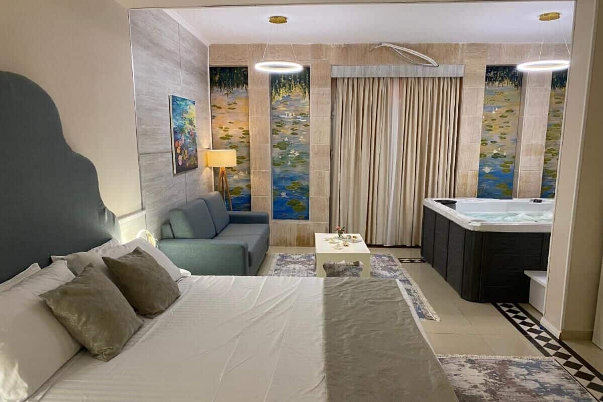 Habitación de hotel con una cama grande, un sofá, una mesita, un escritorio y un baño con bañera.