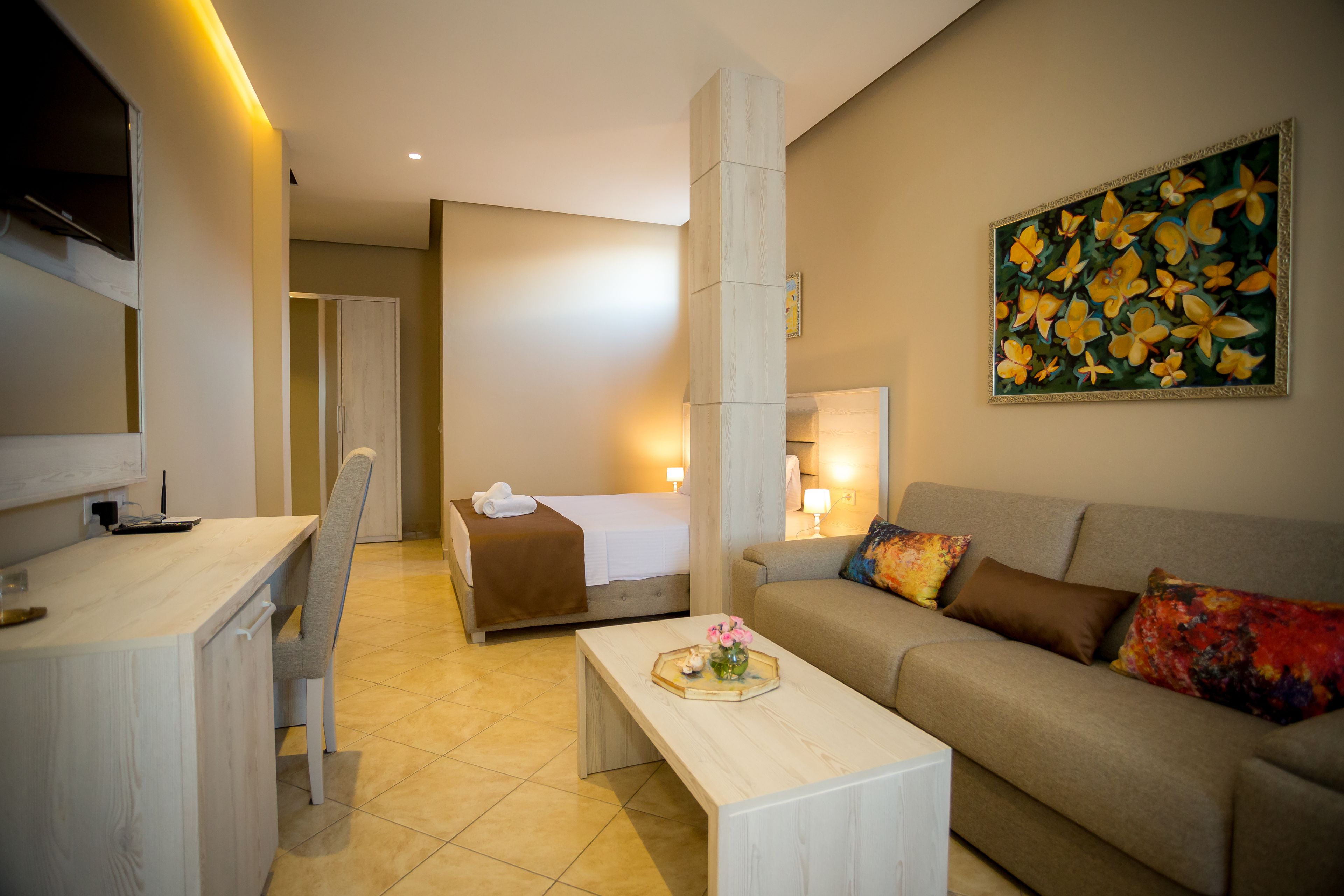 Une chambre d’hôtel avec un lit, un canapé, un bureau et un tableau au mur.