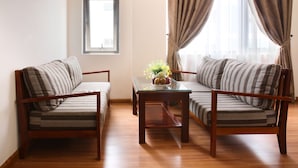 A living room with two sofas, a glass coffee table, and a window with curtains. - Kingdom Hotel (Da Nang)