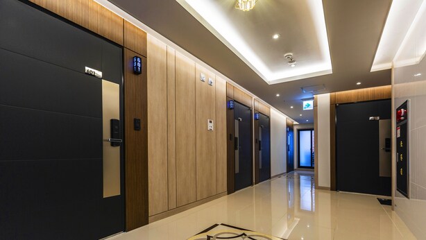 A modern hotel corridor with a polished floor, wooden paneling, and a digital elevator display. - Karat Hotel (Busan)