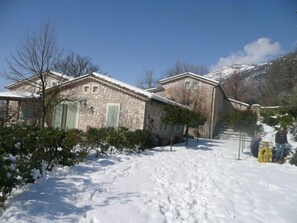 A stone house with a snow-covered roof and a clear blue sky.