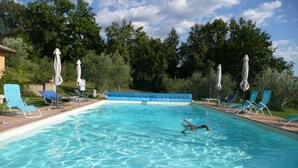 A swimming pool with clear blue water, surrounded by lounge chairs and umbrellas. - Il Bruco B&B (San Donato Val Di Comino)