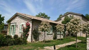 A stone house with a tiled roof, green shutters, and a garden with flowering plants. - Il Bruco B&B (San Donato Val Di Comino)