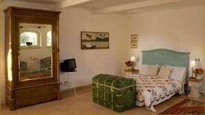 A bedroom with a bed, a dresser, a green trunk, and a painting on the wall. - Il Bruco B&B (San Donato Val Di Comino)