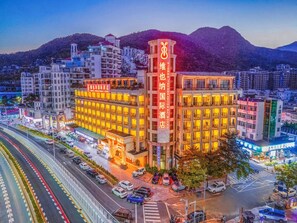 A multi-story hotel with a prominent sign, surrounded by other buildings and a busy street.