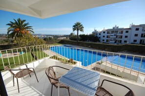 A balcony with a pool, wicker chairs, and a table. - Solar dos Vilarinhos (Albufeira)