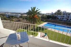 A balcony with a view of a swimming pool, palm trees, and surrounding buildings. - Solar dos Vilarinhos (Albufeira)