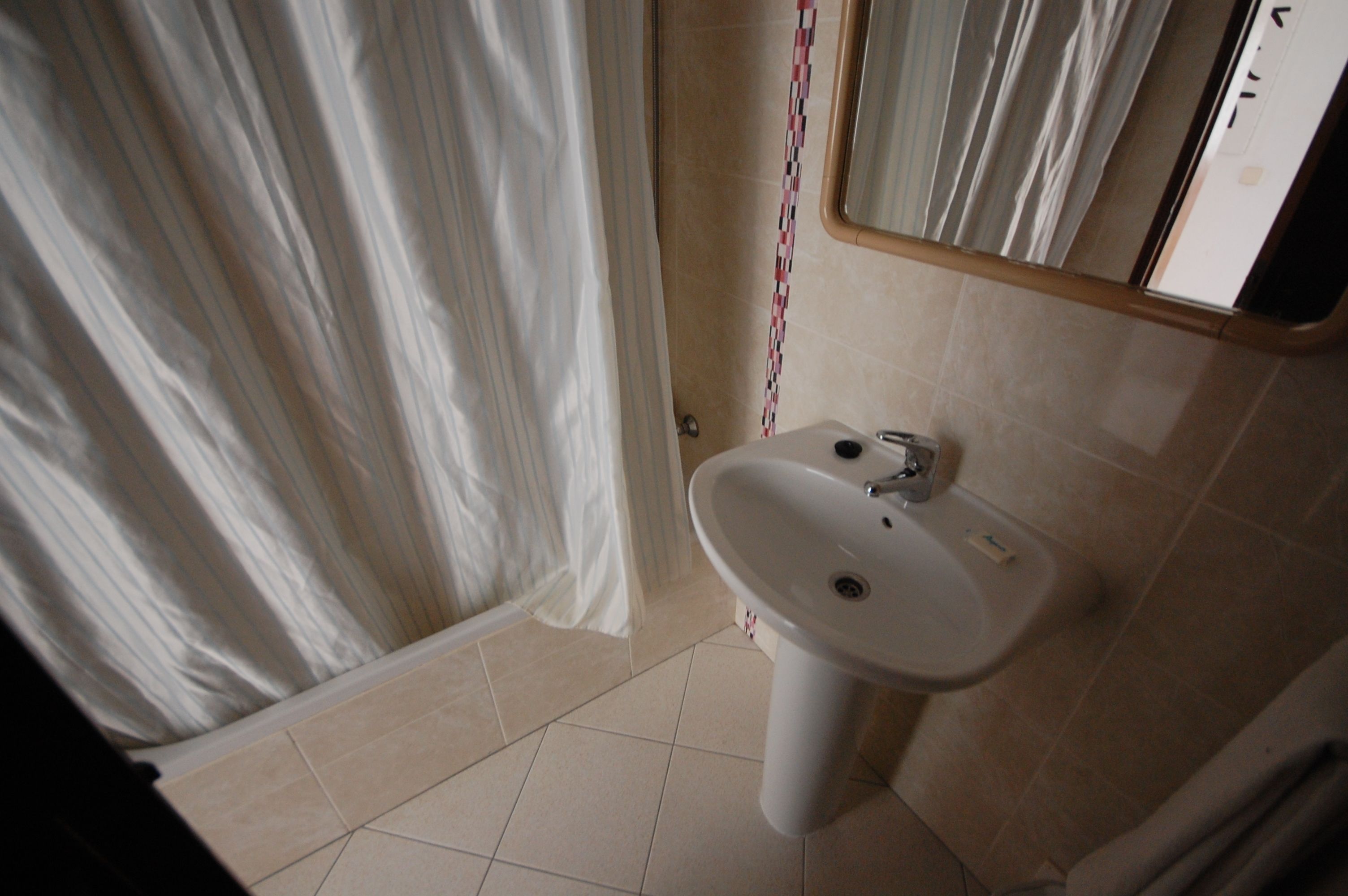 A bathroom with a white sink, a mirror, and a shower curtain.