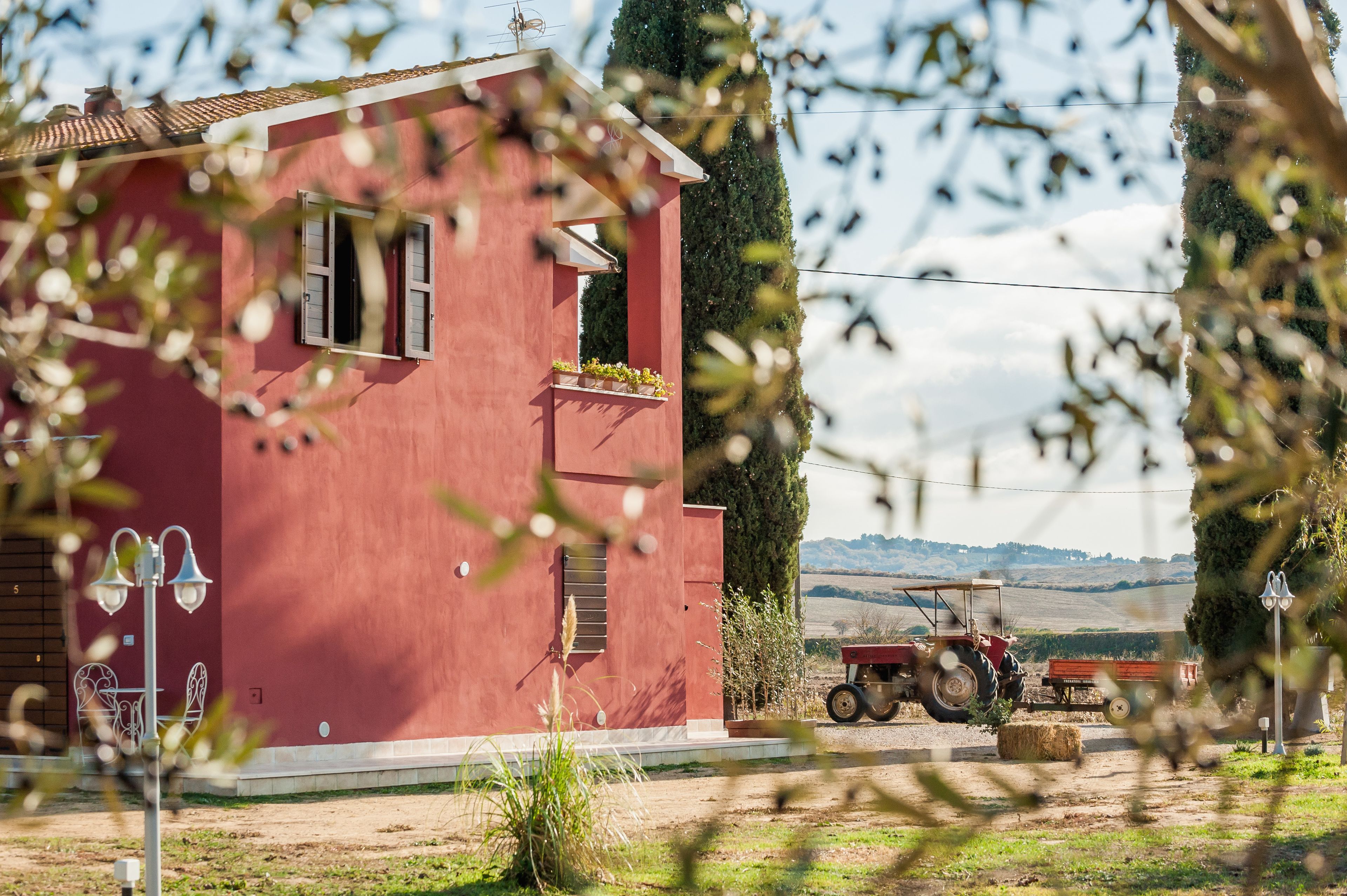 Un bâtiment rouge avec une fenêtre, un lampadaire et un tracteur en arrière-plan.