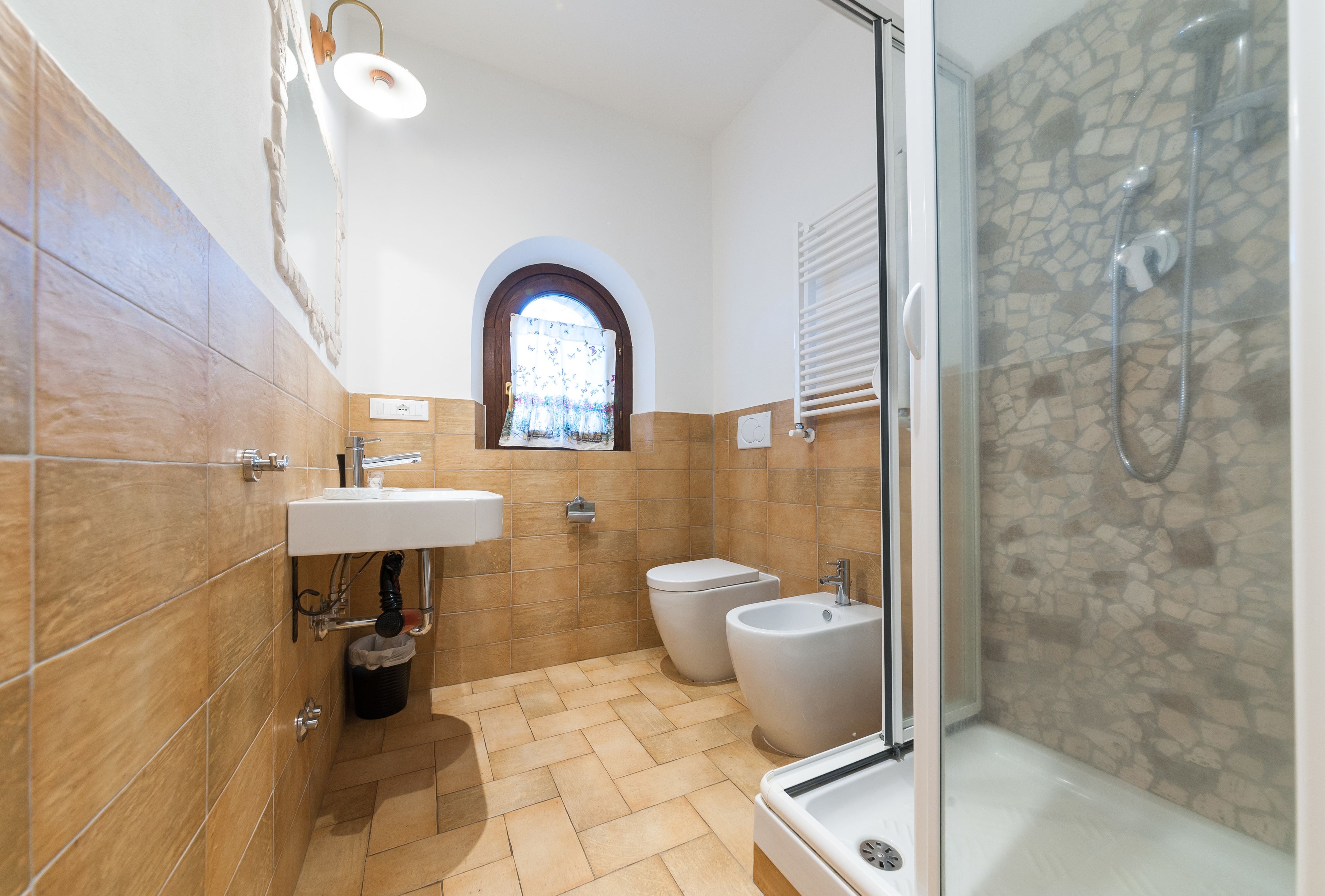 Baño con ducha, inodoro, bidé, lavabo y una ventana pequeña.