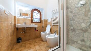 Un bagno con due servizi igienici, un bidet, un lavandino e una zona doccia.