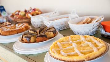 Un'ampia varietà di dolci, torte e pasticcini esposti su piatti e cesti.
