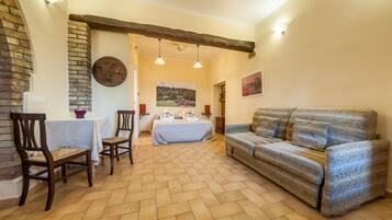 A cozy room with a bed, a sofa, a dining table with chairs, and a fireplace.