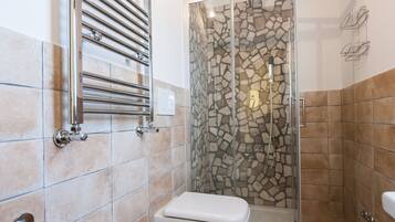 A bathroom with a shower, two sinks, and a toilet.