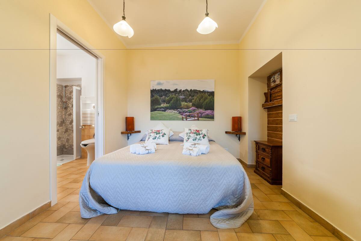 Un dormitorio con una cama, un cuadro en la pared y un aparador de madera.