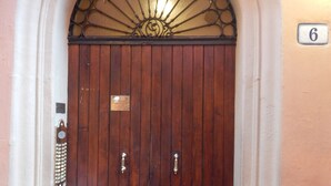 A wooden double door with a decorative metal grille above it, set within an arched doorway.