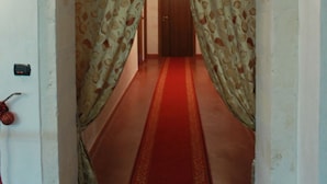 A hallway with a red carpet, an ornate archway, and a patterned curtain. - Villa Flora Baia degli Ulivi (Santeramo in Colle)