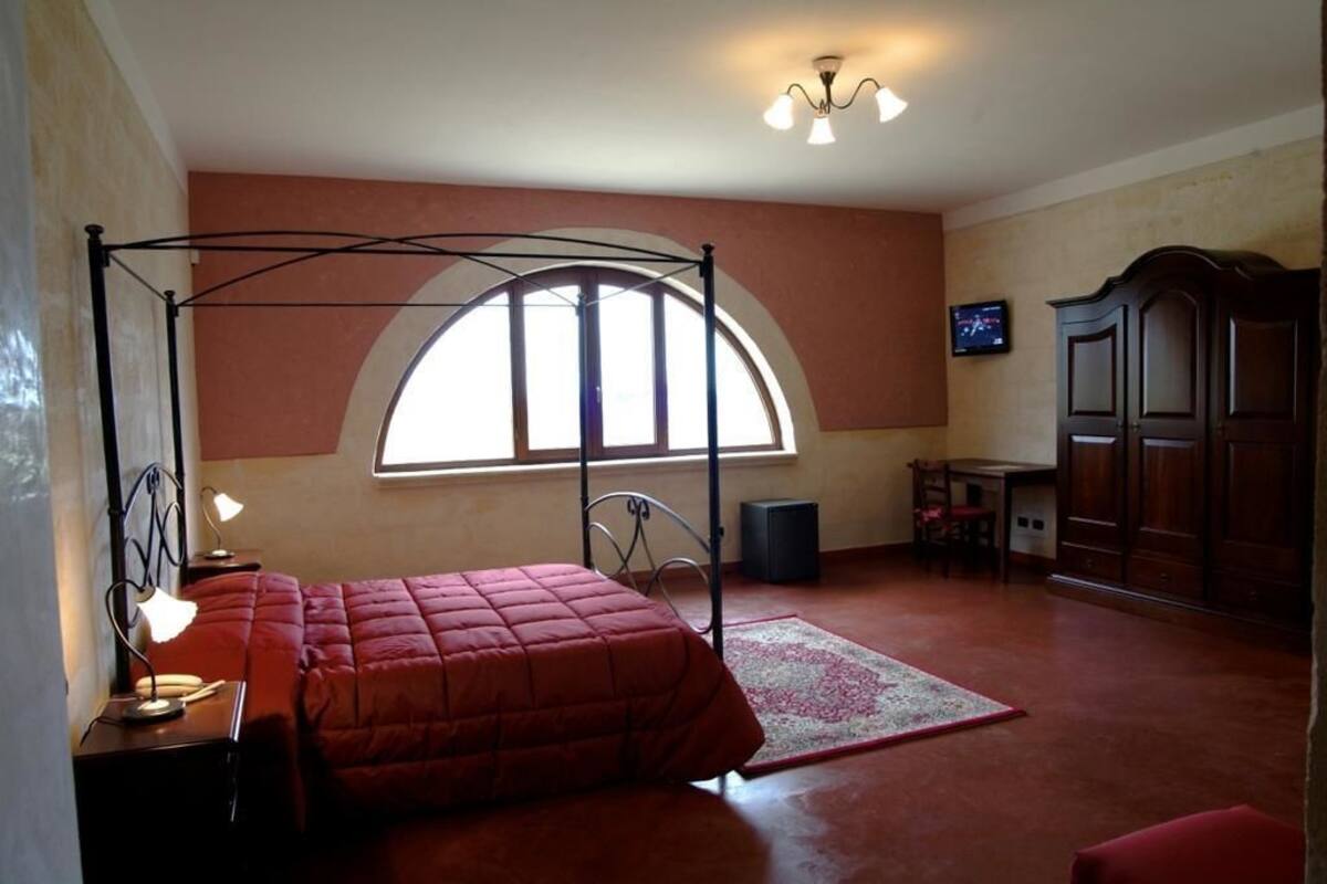 Une chambre à coucher avec un lit à baldaquin, un bureau avec une chaise, une télévision et une armoire.
