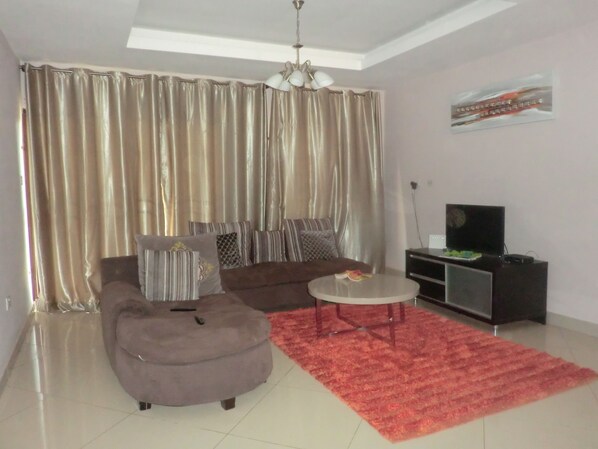 A living room with a sofa, ottoman, coffee table, and a TV stand.