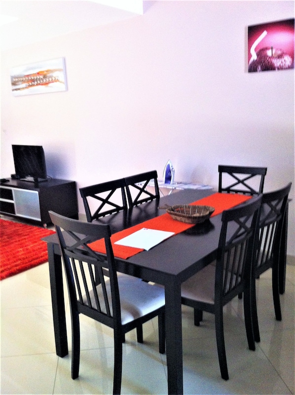 A dining area with a black table, four chairs, and a red placemat.