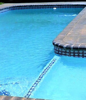 A swimming pool with a tiled edge and a visible line marking the shallow end.