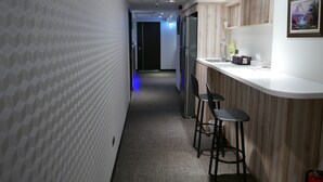 A corridor with a patterned wall, a bar area with stools, a refrigerator, and a sink. - Ours Inn II (Taipei)