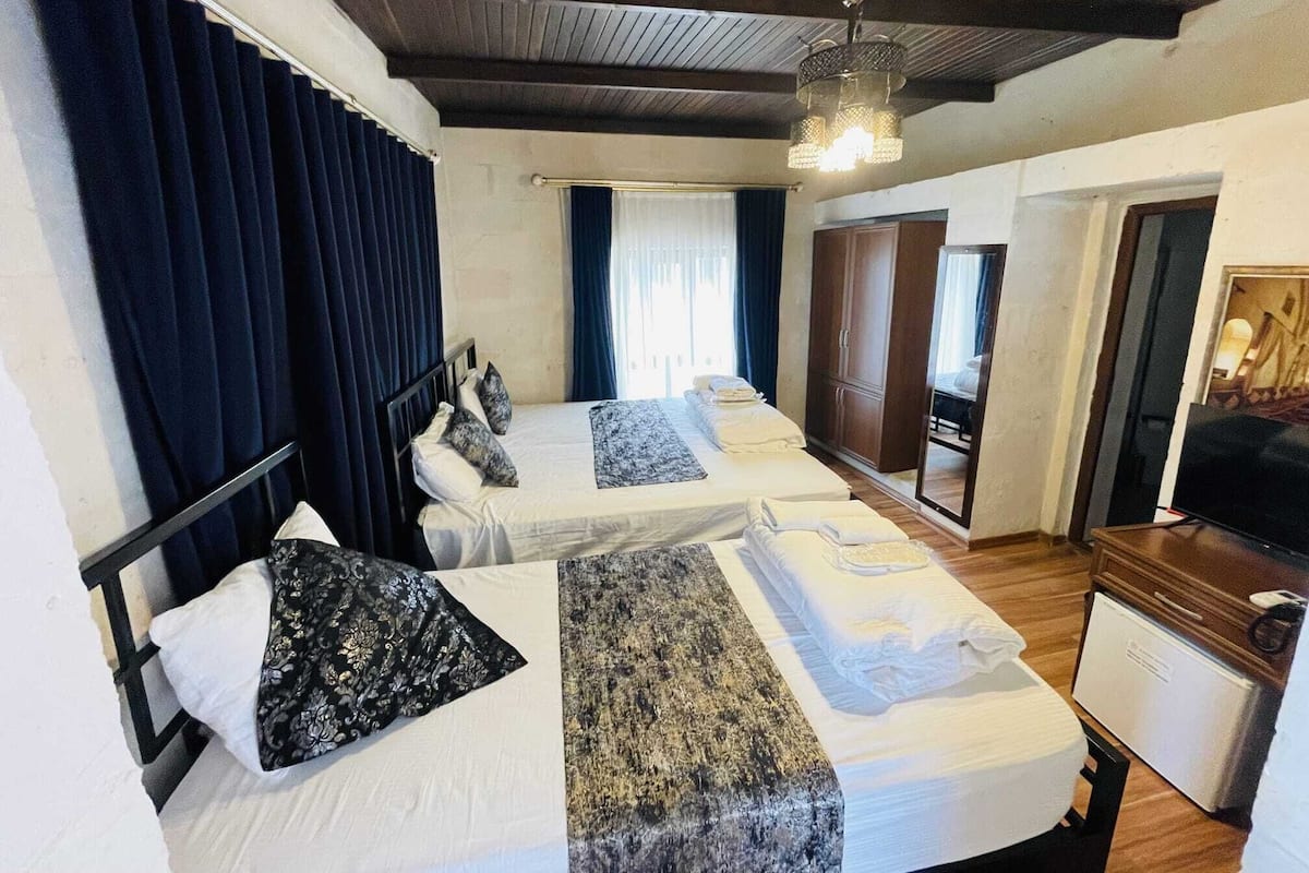 A hotel room with two beds, a wardrobe, a television, and a small kitchenette.