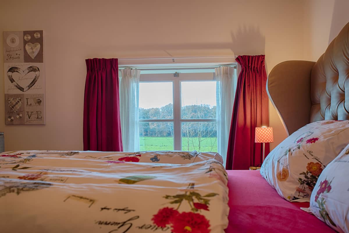 A bedroom with a bed, a window with curtains, a lamp, and wall decorations.
