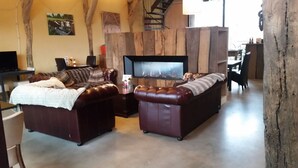 Una sala de estar acogedora con dos sofás de cuero, un televisor de pantalla plana y una chimenea.