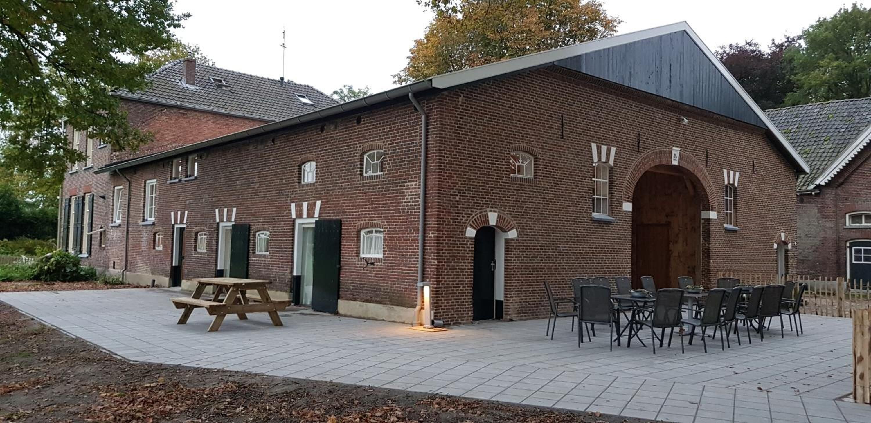 A brick building with a large arched entrance, a picnic table, and outdoor seating area.