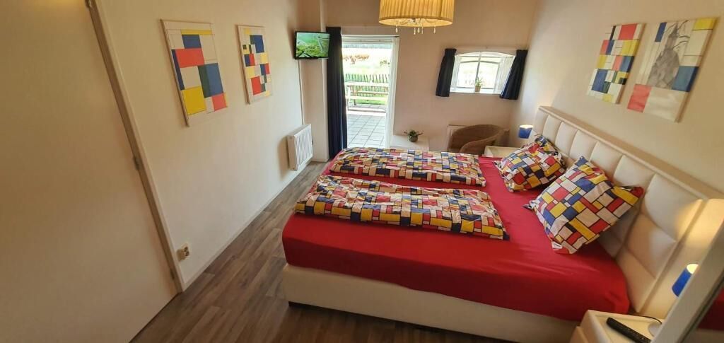 A bedroom with a bed, a bedside table, a chair, and a window.