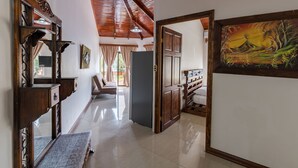 A hallway with a wooden ceiling, a painting on the wall, and a door leading to another room. - In the heart of the city (La Fortuna)
