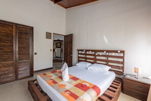 Ein Schlafzimmer mit einem hölzernen Bett, einem Nachttisch, einem Spiegel und einem Kleiderschrank.
