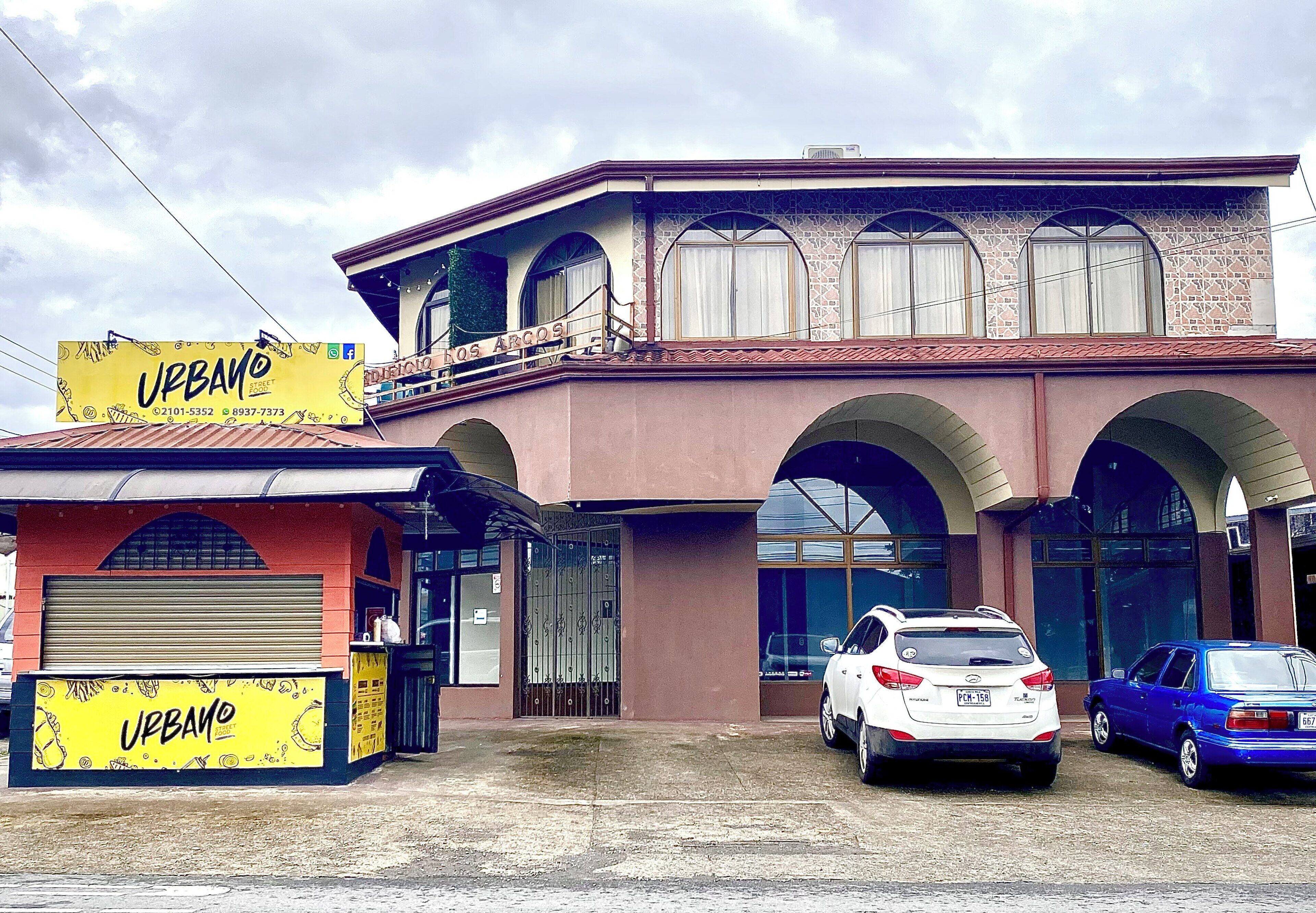 A building with a yellow sign reading "URBANO" and a gated entrance.