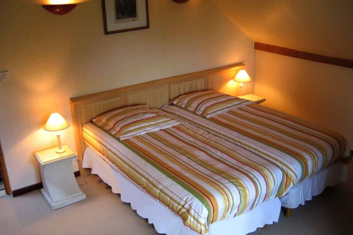 A neatly made bed with striped bedding, two bedside lamps, and a framed picture on the wall.