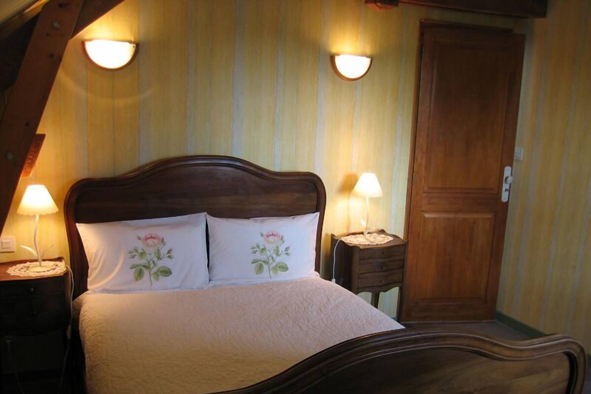 A bedroom with a wooden bed, two bedside lamps, and a wooden door.