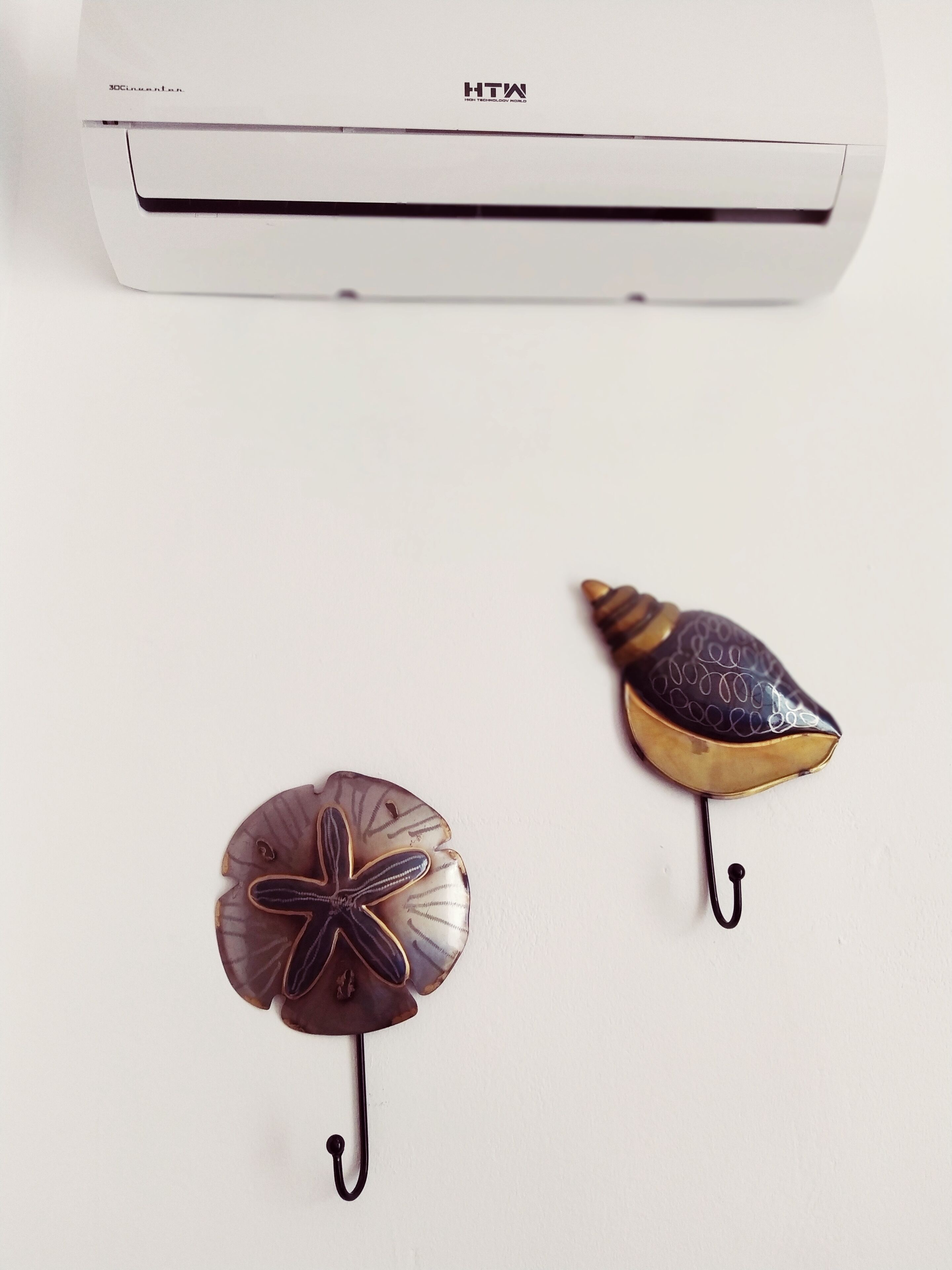 A white air conditioning unit with the brand name "HTW" and two decorative items hanging below it.